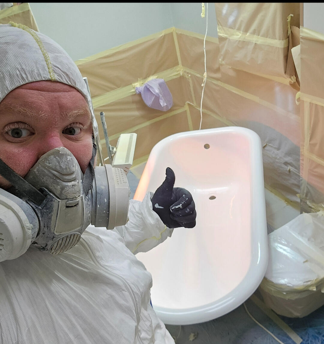 photo of glossy baths re-enamelling owner Seamus with a thumbs up, in ppe, in a room full of masking up and a completed bath in Swansea